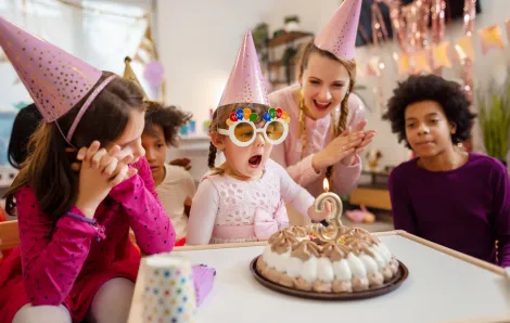 Little girl blowing out birthday candles at birthday party