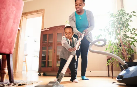 Little boy helping his mom vacuum during spring cleaning