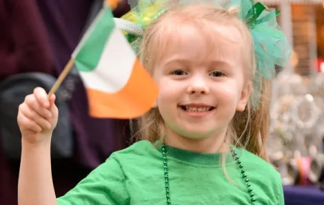 A young girl waves a flag at a local Seattle St. Patrick's Day parade event