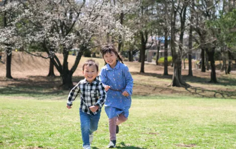 boy and girl running through cherry blossom trees during spring break