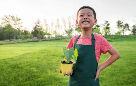 Smiling boy holding a seedling to plant for Earth Day