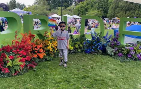 A kid of about 12 years old holds a Pride sign during Pride in Seattle