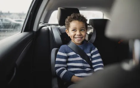 boy smiles in the backseat of a car