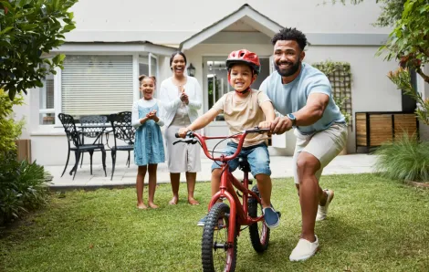 kid learning to ride a bike at home with their family