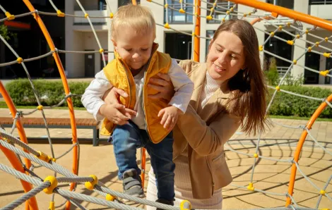 mom holding a child on a climbing structure at a park