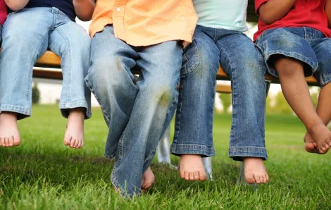 Young children sitting on a bench in the grass all wearing jeans. Target Denim Take Back Event