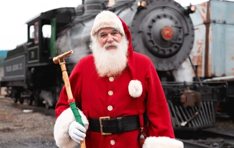 Santa stands in front of a Christmas train on the Mt. Rainier Scenic Railroad, a holiday train ride with tickets on sale now
