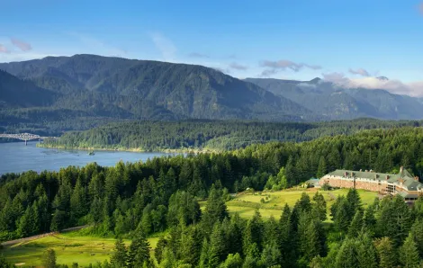 aerial view of the exterior of Skamania Lodge, nestled in the forest with mountains behind it