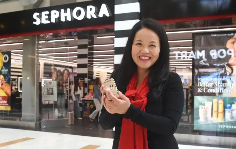 woman holding up a free gift from Sephora on her birthday