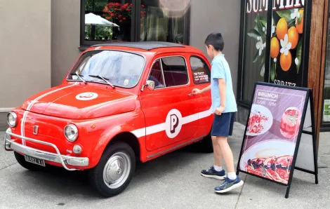 young boy walking up to vintage Fiat outside Piatti, a fun Seattle brunch spot