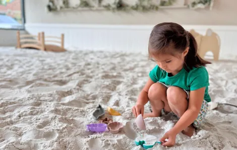 young girl scooping sand at an indoor sandbox in Issaquah