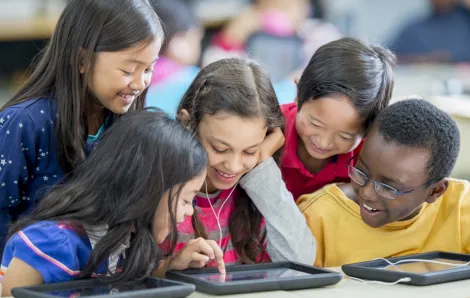 kids gathered around a tablet at school