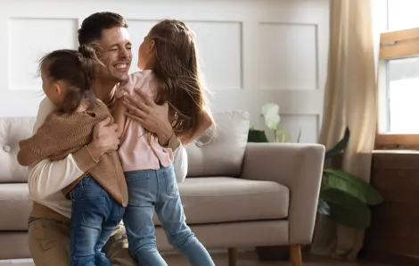 dad hugging two young daughters
