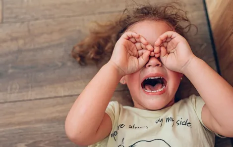 a young girl crying on the floor with hands over eyes after getting home from school and having a tantrum