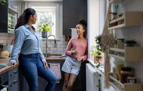 mom and teen daughter talking in the kitchen