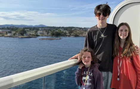 three kids standing on the deck of a cruise ship heading to Alaska