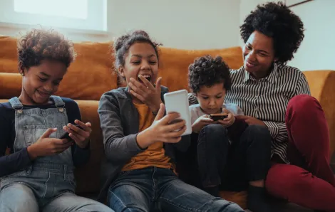 mom and three kids playing cell phone game