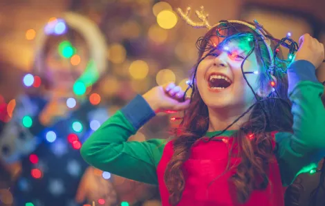 little girl laughing and playing with holiday lights