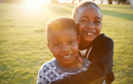 Black History Month events with smiling African American boy and girl hugging each other. 