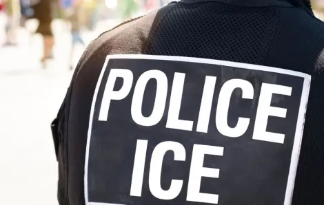 POLICE ICE marking on the back of a hi-visibility stab proof vest worn by a police officer