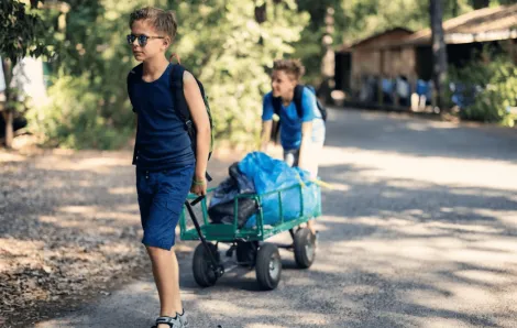 Boys at summer camp with luggage trolley heading to their cabin