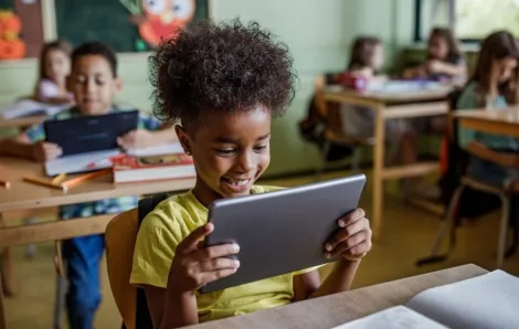 Happy elementary student using touchpad in a class