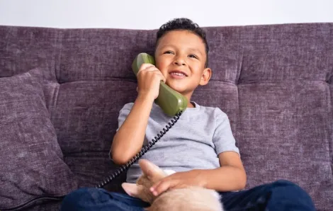 happy little boy talking on vintage green landline phone at home