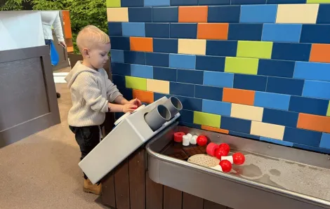 young child playing at the water play area at KidsQuest, offering discounted weekend admission for families Super Bowl weekend