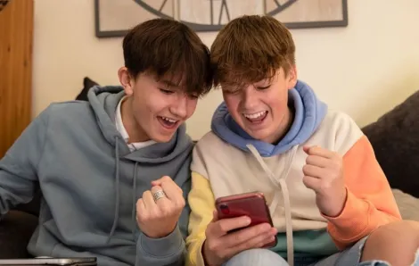 Two teenage boys playing and gambling on smart phones