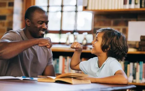 Teacher and student giving each other a high five in a library