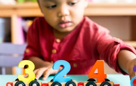 Little boy playing with mathematics wooden toy at child care