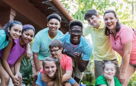 Group of teens and camp staff smiling together outdoors at camp