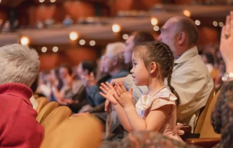 little girl clapping hands in a concert hall