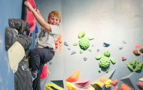 young boy climbing at an indoor rock climbing gym in Seattle