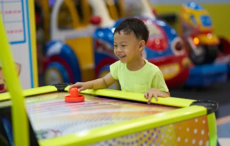 little boy playing air hockey at an arcade