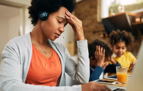 overcommitted mom looking stressed out with kids in the background