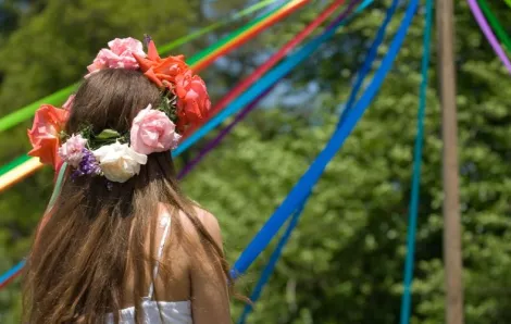 A girl with flowers in her hair participates in a May Day pole dance