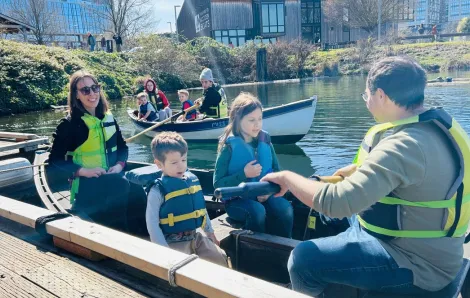 family of four rowing in a rowboat on South Lake Union in Seattle at The Center for Wooden Boats