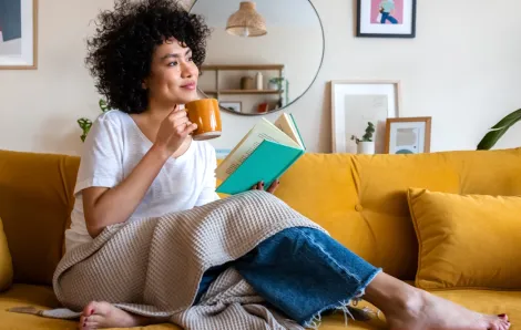 woman sitting on a couch with a cup of coffee and a book