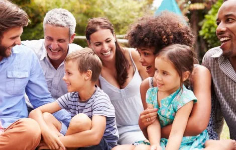 Adults and kids sitting on the grass in a garden