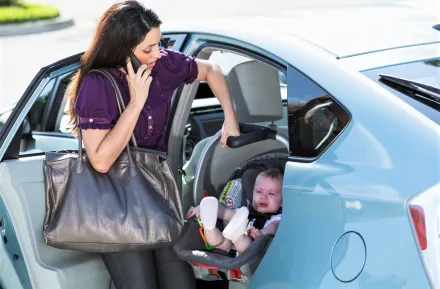 Mom leaving for work and child care with child in infant carseat, bag, phone