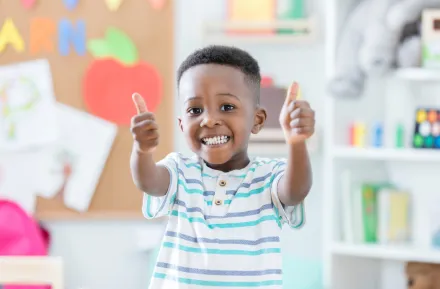 Boy holding two thumbs up at preschool