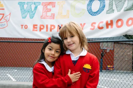 two girls hugging in front of school