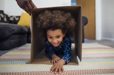 a child crawls through a cardboard box, part of an indoor obstacle course challenge