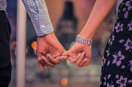 Couple holding hands with linked pinky fingers