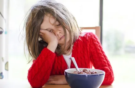 child sleeping at breakfast table who needs to adjust to daylight saving time change