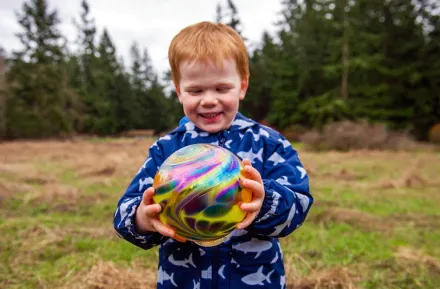 young child holding a glass float found during Northwest Glass Quest, a glass float hunt on Camano Island