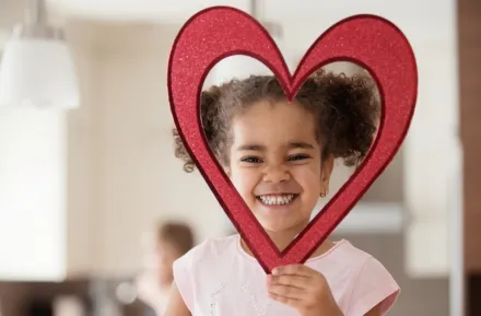 little girl holding a heart shape around her head