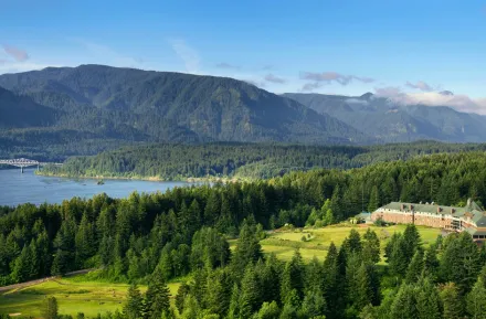 aerial view of the exterior of Skamania Lodge, nestled in the forest with mountains behind it