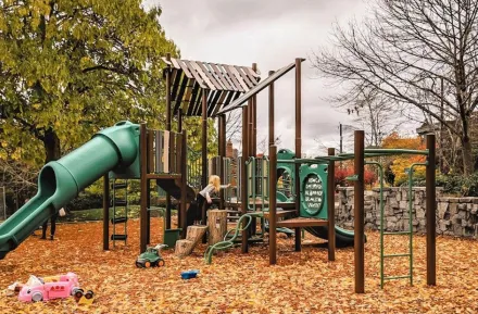 a young girl climbs on a playground in Seattle on a rainy day